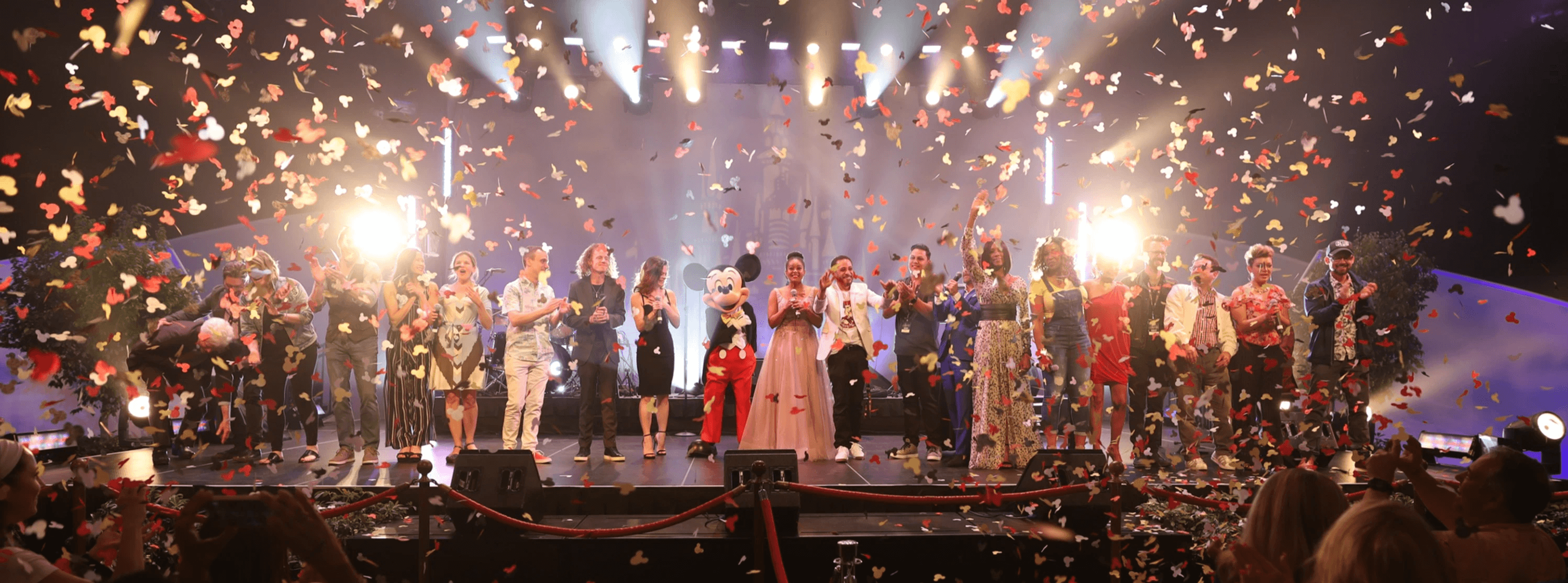 Mouseketeers and Mickey Mouse celebrating amid confetti